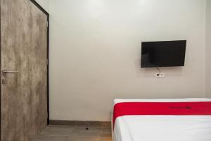 een slaapkamer met een bed en een tv aan de muur bij RedDoorz Plus at Eskole ITERA Lampung in Lampung