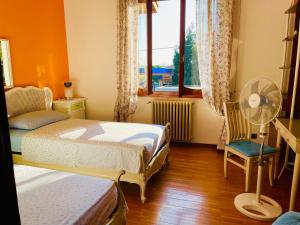 een slaapkamer met 2 bedden, een ventilator en een raam bij Appartamento tra Monza e Milano in Muggiò