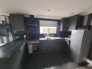 a kitchen with black cabinets and a white refrigerator at Sanity Sanctuary in Leysdown-on-Sea +10 photos