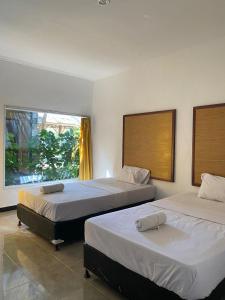 a bedroom with two beds and a window at Vico hotel in Nusa Dua