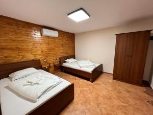 a bedroom with two beds and a wooden wall at HOTEL FLAVIA in Poliçan
