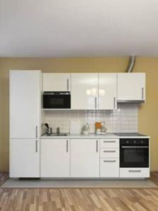 een keuken met witte kasten en een zwart apparaat bij Apartment Vltavska A in Praag