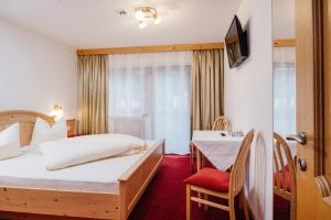 una camera d'albergo con letto e tavolo di Hotel Andrea a Zams