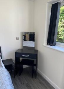 a bedroom with a black desk and a mirror at Studio apartment in Harefield in Harefield