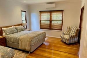 a bedroom with a bed and a chair and a window at Pine View Cottage - Margaret River in Cowaramup