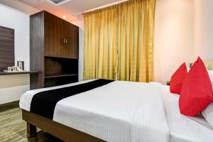 een slaapkamer met een wit bed met rode kussens bij Collection O 73565 J J Global Exotics Stays in Bangalore