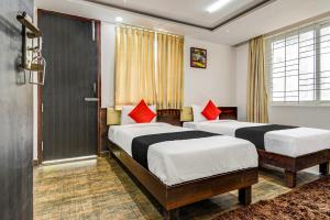 two beds in a hotel room with red pillows at Collection O 73565 J J Global Exotics Stays in Bangalore