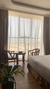 a bedroom with a bed and chairs and a large window at Fakher Yanbu 3 Furnished Units in Yanbu