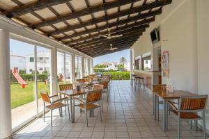 a restaurant with tables and chairs and windows at Apartamentos Sa Caleta in Sa Caleta