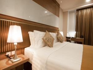 a bedroom with a large white bed with a lamp at Garden Sentral Hotel in Kuala Belait