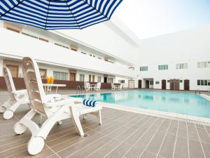 a pool with chairs and an umbrella in a building at Garden Sentral Hotel in Kuala Belait