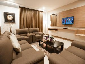 a living room with two couches and a tv at Garden Sentral Hotel in Kuala Belait