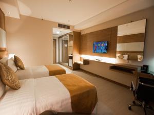 a hotel room with two beds and a television at Garden Sentral Hotel in Kuala Belait