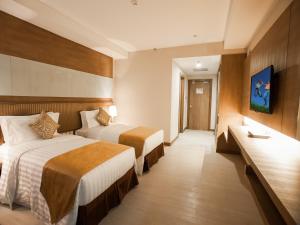 a hotel room with two beds and a television at Garden Sentral Hotel in Kuala Belait