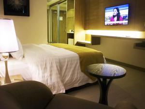 a hotel room with a bed and a chair and a tv at Garden Sentral Hotel in Kuala Belait