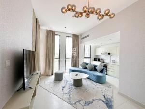 uma sala de estar com um sofá azul e uma televisão em ANW Vacation Homes - One bedroom apartment Afnan 4 Midtown Dubai Production City no Dubai