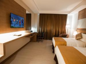 a hotel room with two beds and a desk at Garden Sentral Hotel in Kuala Belait