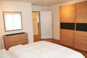 sypialnia z białym łóżkiem i drewnianą komodą w obiekcie Nest - Baarerstrasse 55 w mieście Zug