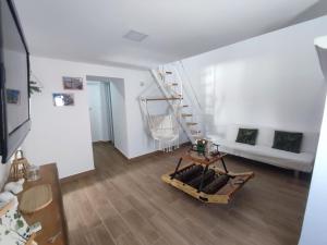 a white living room with a wooden floor and a staircase at Rua da Avó in Barbacena