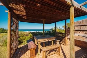a wooden pergola with a picnic table and a bench at Seester Strandhuis in Jeffreys Bay