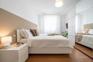 a white bedroom with a bed and a mirror at [Via Indipendenza] – Attico di lusso con Piscina in Bologna