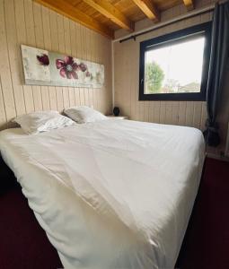 ein weißes Bett in einem Zimmer mit Fenster in der Unterkunft Chalet indépendant 2000m2 de terrain 3 chambres 