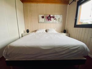 ein großes weißes Bett in einem Zimmer mit Fenster in der Unterkunft Chalet indépendant 2000m2 de terrain 3 chambres 