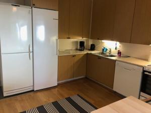 eine Küche mit weißen Geräten und Holzschränken in der Unterkunft Apartment Retkeilijäntie 18, Kuopio in Kuopio