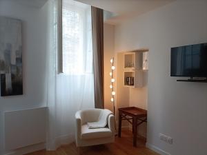 a living room with a white chair and a television at Villa Buffon in Angers