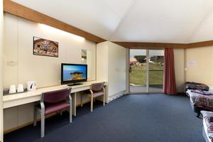 a room with a desk with a television and chairs at The Station Hotel in Jindabyne
