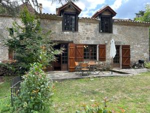 BardouにあるManoir du Suquetの庭にテーブルと椅子を配置した石造りの家