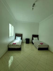 2 camas num quarto com piso em azulejo em Appartement Tanger 3 em Tânger