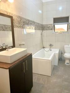 ein Badezimmer mit einem Waschbecken, einer Badewanne und einem WC in der Unterkunft SAFARI LAKE VIEW SUITES, KITENDE in Entebbe