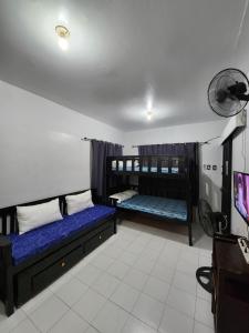 a room with two bunk beds and a fan at Casita Mia - Guest House for 9pax with WIFI, NETFLIX, YOUTUBE, KARAOKE, CAN COOK and BBQ in Malolos