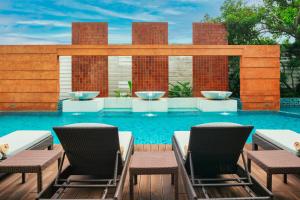 a swimming pool with two chairs and a table at The Grand Napat in Chiang Mai
