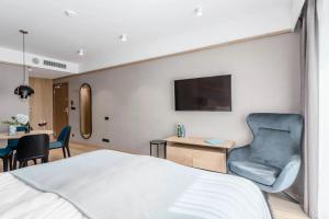 a hotel room with a bed and a chair and a tv at Deo Plaza Old Town Gdańsk - Praia Apartaments in Gdańsk