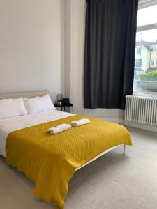 - une chambre avec un lit doté d'une couverture jaune dans l'établissement Wonderful 3 Bed Flat with Private Garden in Wimbledon - 1 The Queens, à Londres