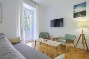 een woonkamer met een bank, 2 stoelen en een tafel bij Charming Lavapies Center in Madrid