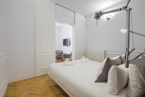 een witte slaapkamer met een wit bed en een spiegel bij Charming Lavapies Center in Madrid