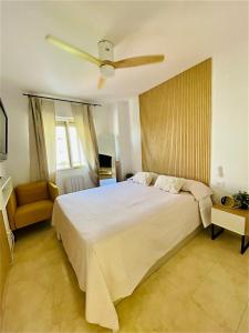 - une chambre avec un grand lit et un ventilateur de plafond dans l'établissement Bonito apartamento en la playa, à Benicàssim