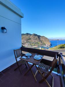 una mesa y sillas en un balcón con vistas al océano en Machico Terrace, en Machico