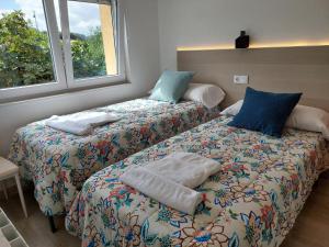 2 nebeneinander sitzende Betten in einem Schlafzimmer in der Unterkunft Apartamentos La Tata in Avilés