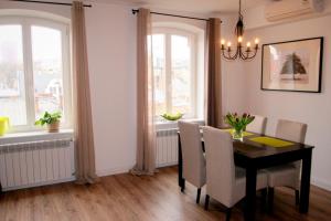 uma sala de jantar com mesa, cadeiras e janelas em Apartament Kwiatowa 3/22 em Poznań