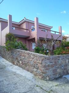 a pink house with a stone retaining wall at Calma in Perdika
