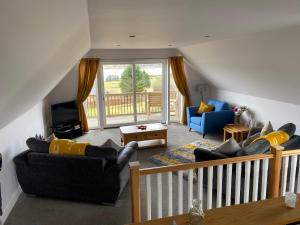 Lochview Chalet في Eyre: غرفة معيشة مع كنبتين وشرفة