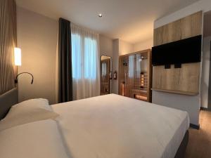 a bedroom with a large white bed and a flat screen tv at Hotel Leonessa in Brescia