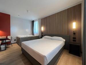 una camera con letto, scrivania e vasca di Hotel Leonessa a Brescia