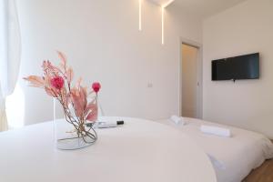 un jarrón de flores sentado encima de una cama en PrimoPiano - Padova 320, en Milán