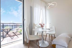 Habitación blanca con mesa, sillas y balcón. en PrimoPiano - Padova 320, en Milán