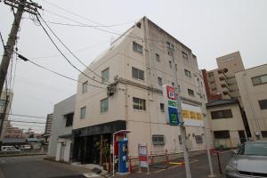 un edificio blanco alto con una gasolinera en una calle en Glocal Nagoya Backpackers Hostel en Nagoya